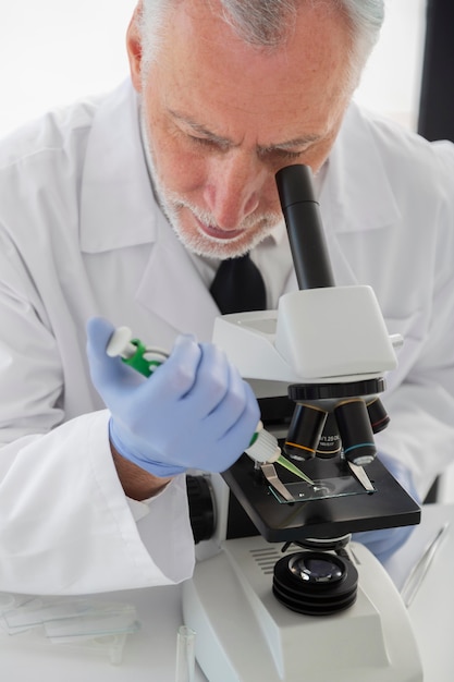 Foto gratuito científico mirando a través del microscopio