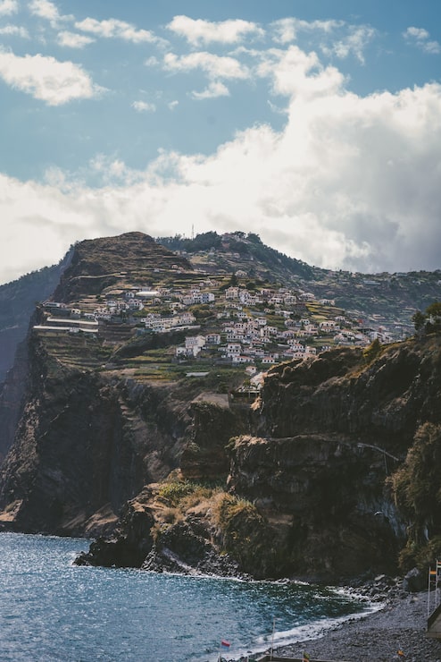 Foto gratuito disparo vertical de edificios en la montaña bajo un cielo azul en funchal, madeira, portugal.