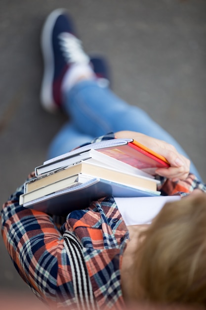 Foto gratuito estudiante con un montón de libros de texto y cuadernos