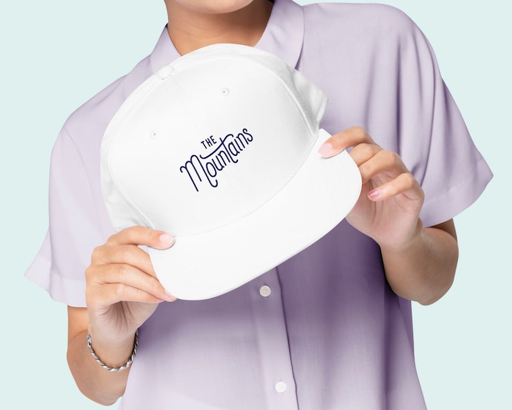 Foto gratuito mano sujetando una gorra de béisbol blanca con el logo de las montañas estampado