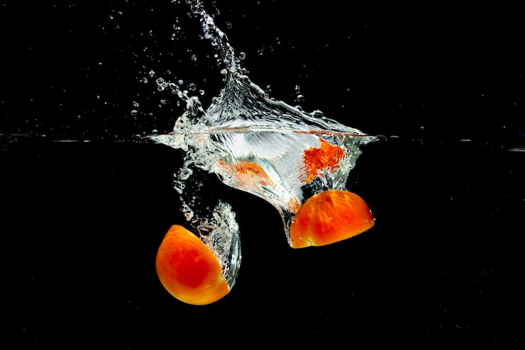 Foto gratuito las mitades de tomate rojo salpicando en agua dulce