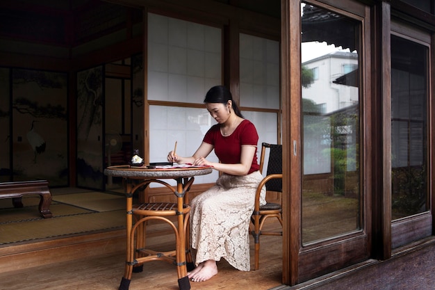 Foto gratuito mujer practicando escritura japonesa en interiores