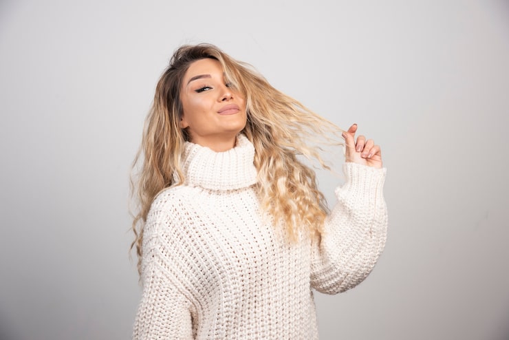 Foto gratuito mujer rubia en traje de invierno jugando con su cabello.