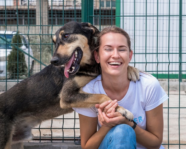 Foto gratuito mujer sonriente jugando en el refugio con perro esperando ser adoptado