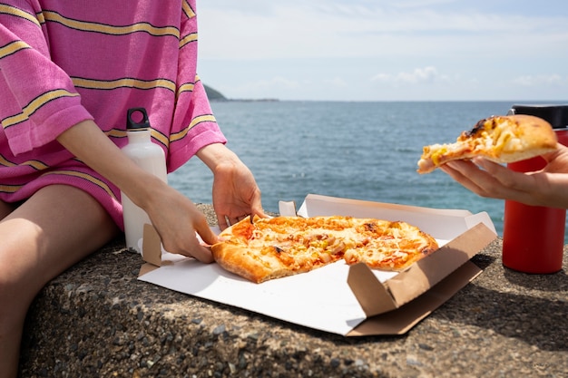 Orang-orang menikmati camilan pizza di luar ruangan