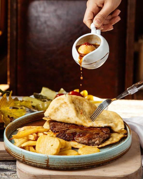 Foto gratuito una persona vierte salsa sobre carne envuelta en flapjack