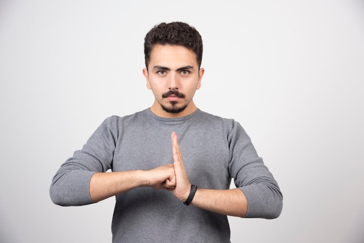 Photo Gratis seorang pria muda berpose dengan tangan di atas dinding putih.