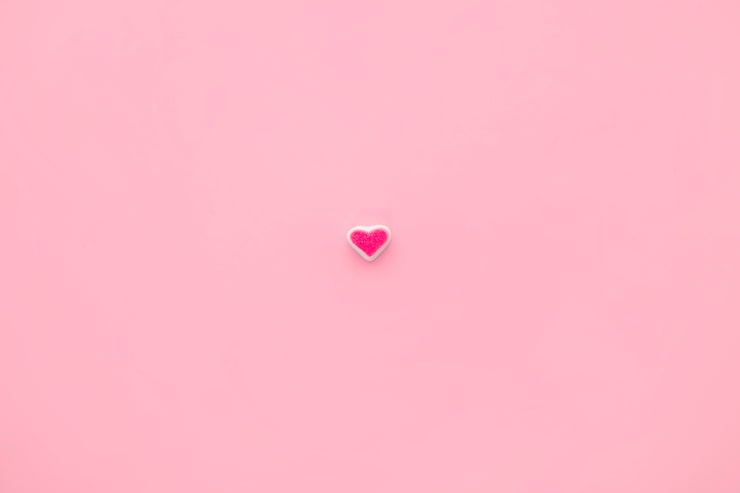 Foto gratuito un solo corazón de caramelo sobre un fondo rosado