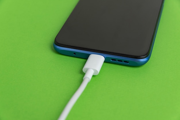 Foto gratuito teléfono celular azul conectado al tipo de cable usb - cargando