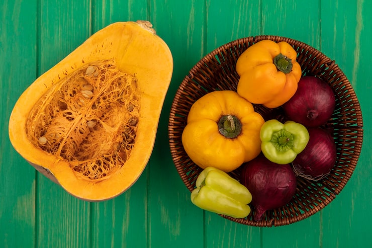 Foto gratuito vista superior de coloridos pimientos en un balde con cebolla roja con calabaza aislado en una pared de madera verde