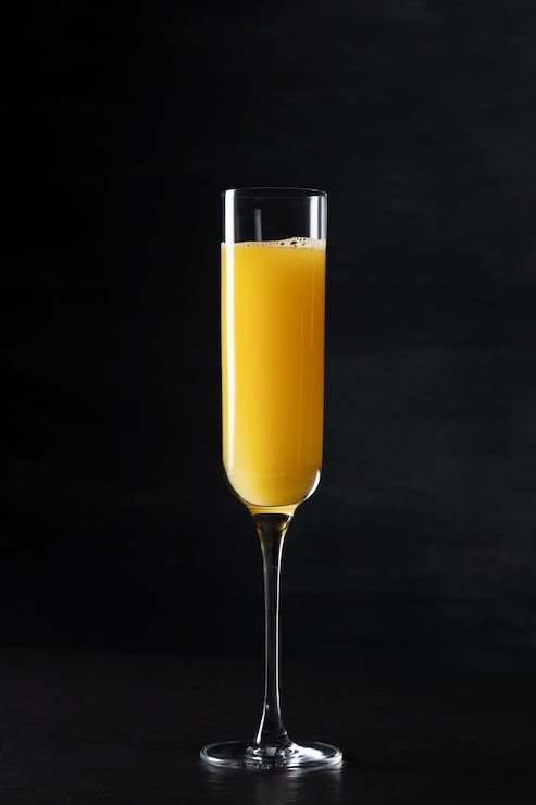 Foto gratuito bicchiere da cocktail mimosa con sfondo scuro