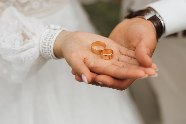 Foto gratuito fasce d'oro nelle mani dello sposo e della sposa