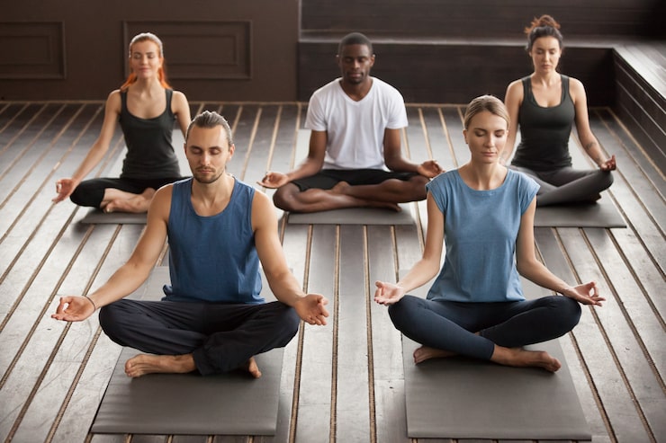 Foto gratuito gruppo di persone giovani yogi seduto in esercizio sukhasana