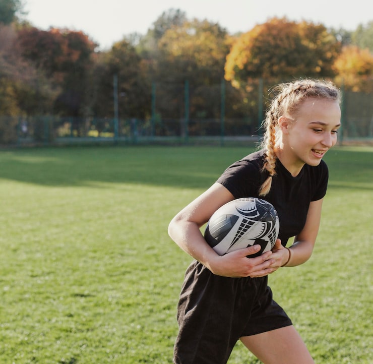 Foto gratuito ragazza bionda che funziona con una sfera di rugby