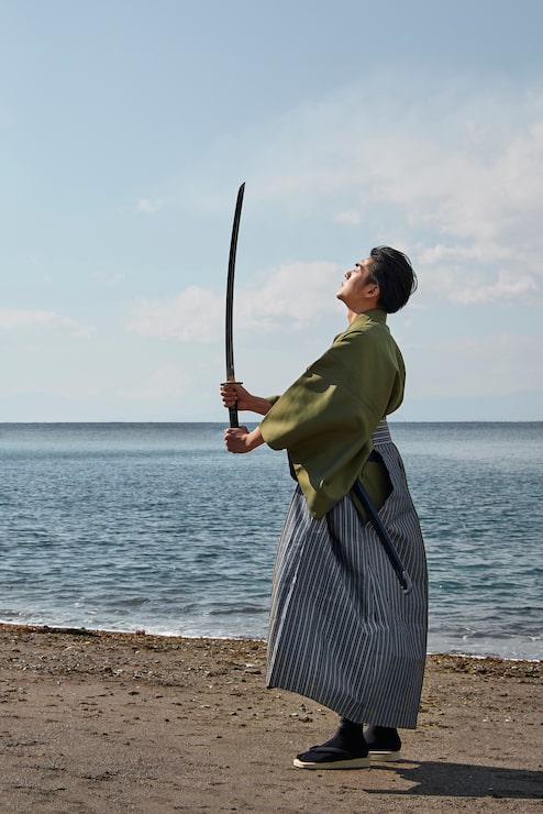 Foto gratuito samurai con la spada in spiaggia
