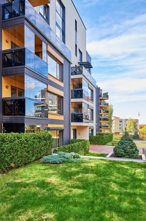 Foto moderno complesso di condomini residenziali con alberi verdi e strutture esterne.