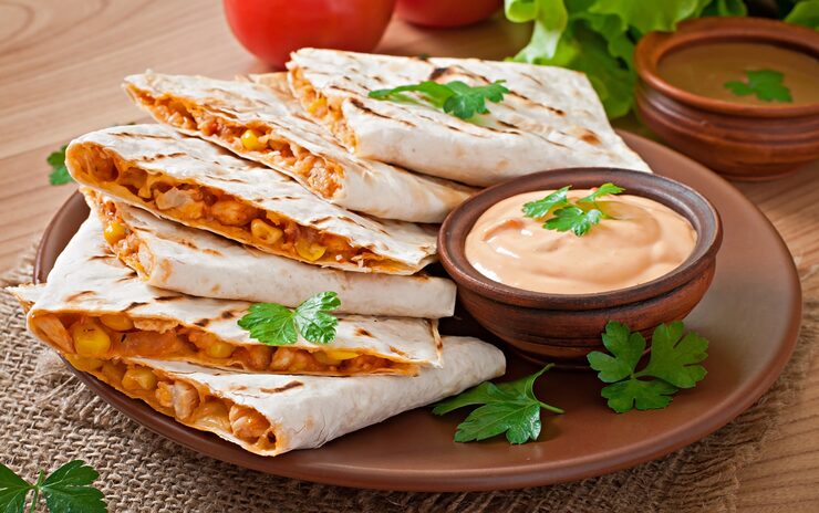 Zdarma Fotografie mexická quesadilla nakrájená s zeleninou a omáčkami na stole