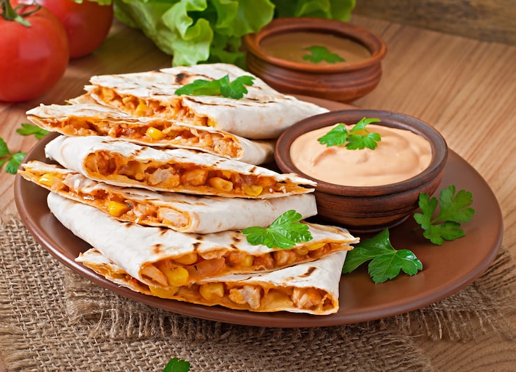Zdarma Fotografie mexická quesadilla nakrájená s zeleninou a omáčkami na stole