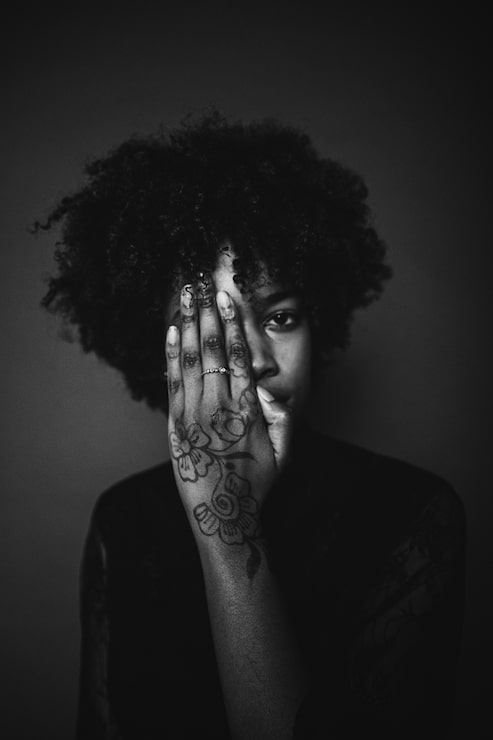 Zdarma Fotografie žena s černými afro vlasy a tetováním na ruce