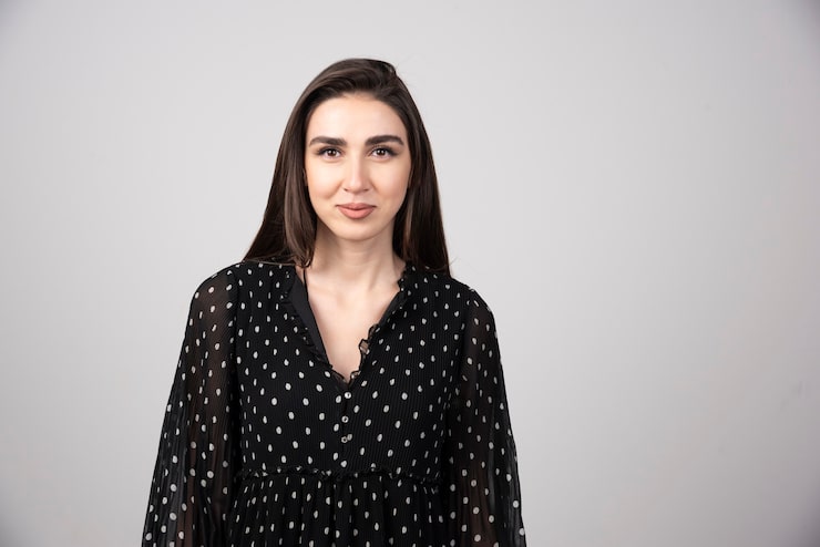 Zdarma Fotografie žena v černých šatech stojí na šedém pozadí.