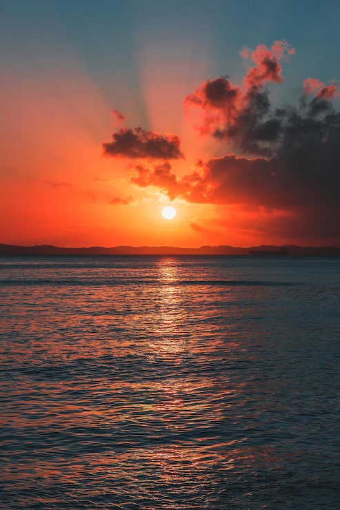 Foto por do sol rosado em meio ao mar com nuvens