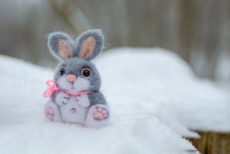 Foto lustiges kaninchen im schneeweihnachts- oder osterkonzept ein grauer spielzeughase sitzt in einer schneewehe gegen den hinter...