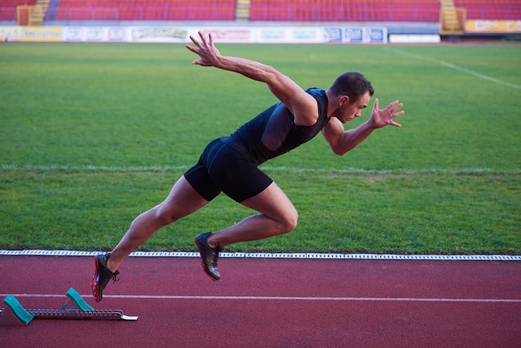 Foto sprinter verlässt startblöcke auf der laufstrecke. explosiver start.