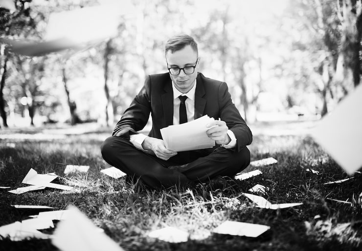 Gratis Foto forretningsmann som sitter med mye spredt papirarbeid
