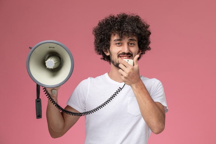 Gratis Foto frontutsikt ung mann smiler og informerer med håndmikrofon