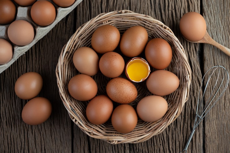 Gratis Foto legg egg i en trekurv på et tregulv.