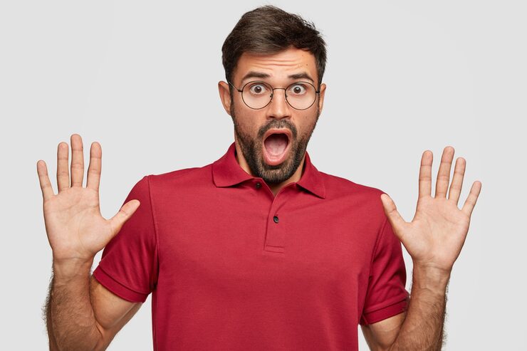 Gratis Foto sjokkert ung emosjonell mann som poserer mot den hvite veggen