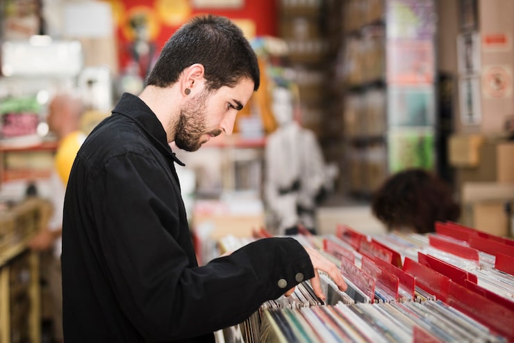 Gratis Foto medium shot, sidevisning af ung mand, der leder efter vinylplader i en butik