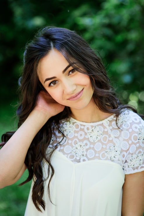 Gratis Foto smilende brunette kvinde i hvid kjole poserer i haven