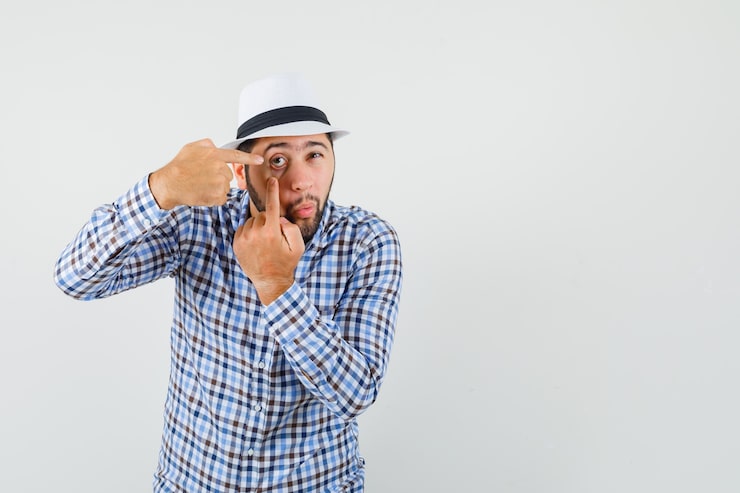Miễn phí Photo một chàng trai trẻ chỉ vào mí mắt bị ngón tay kéo ra, mặc áo sơ mi ca rô