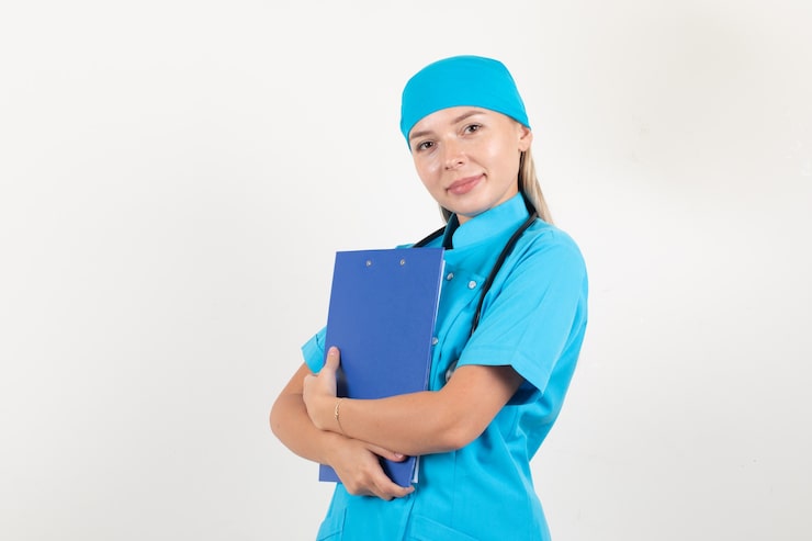 Miễn phí Photo nữ bác sĩ mặc đồng phục màu xanh lam cầm bảng tạm và mỉm cười