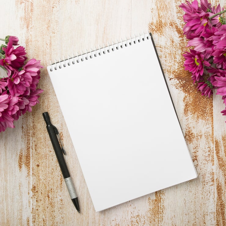 Photo gratuit bloc-notes en spirale avec stylo et fleurs roses sur fond texturé en bois