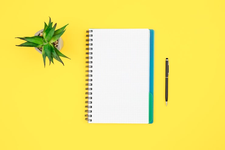 Photo gratuit bloc-notes et stylo sur fond jaune vue supérieure
