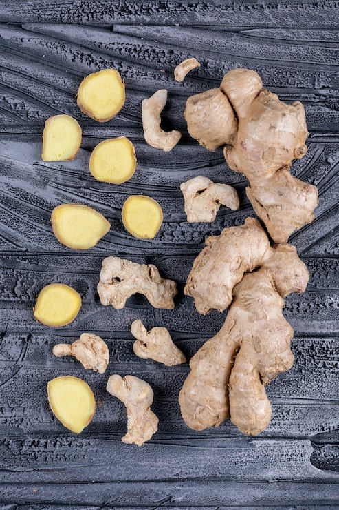 Photo gratuit gingembre plat avec des tranches de gingembre et un fond en bois foncé. verticale