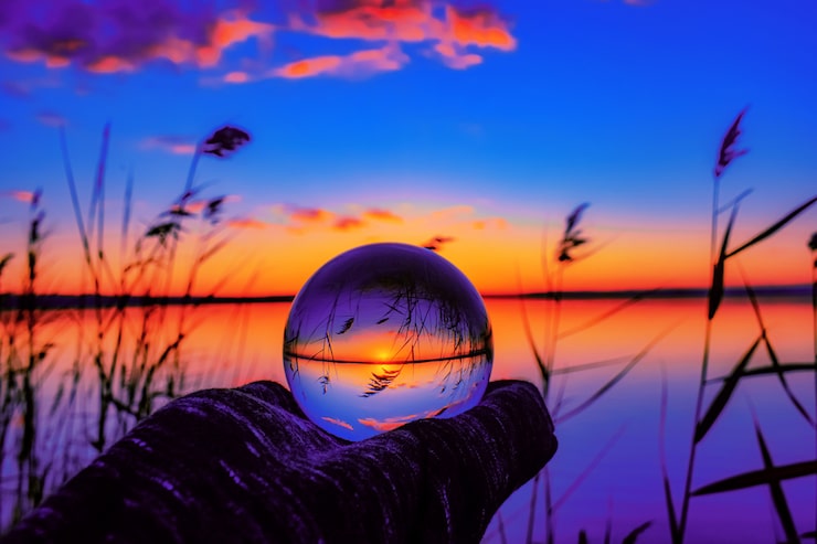 Photo gratuit magnifique photo de mise au point sélective d'une boule de cristal reflétant le coucher de soleil à couper le souffle