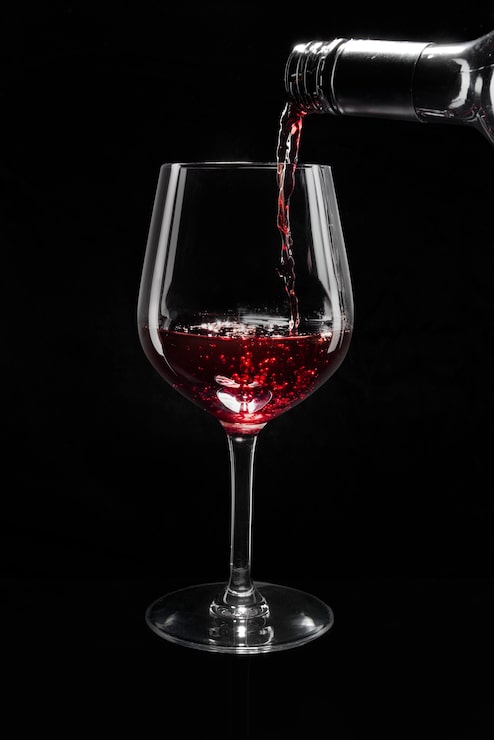 Photo gratuit vin rouge versé dans un verre à vin