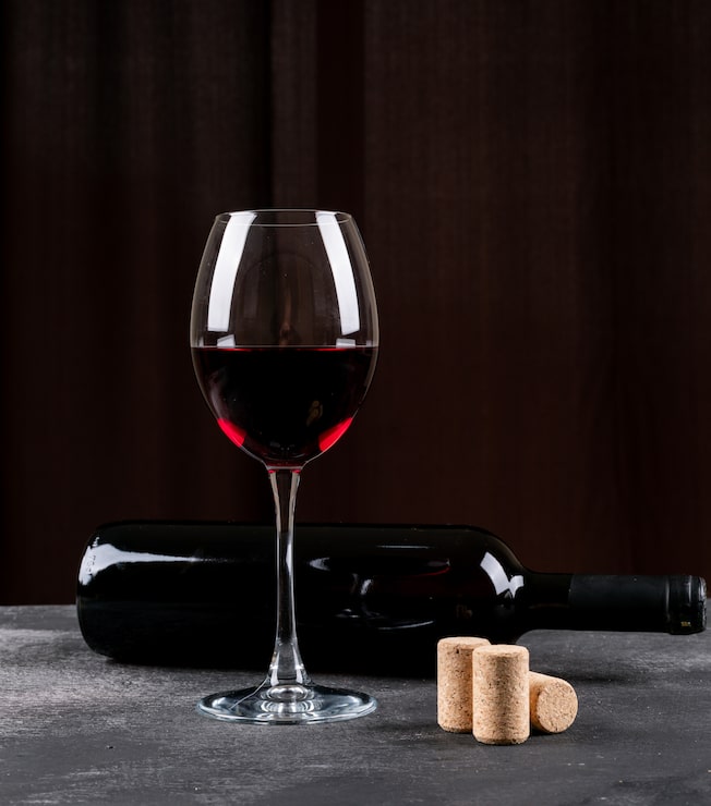 Photo gratuit vue latérale du vin rouge sur une verticale noire