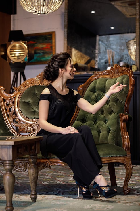 Foto brunette kvinde med frisure i sort tøj sidder på en sofa