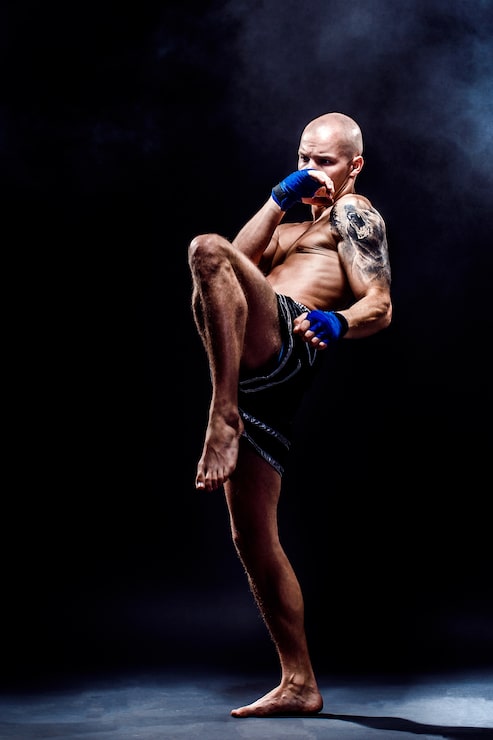 Bild muskulös muay thai-fighter som slår i mörker
