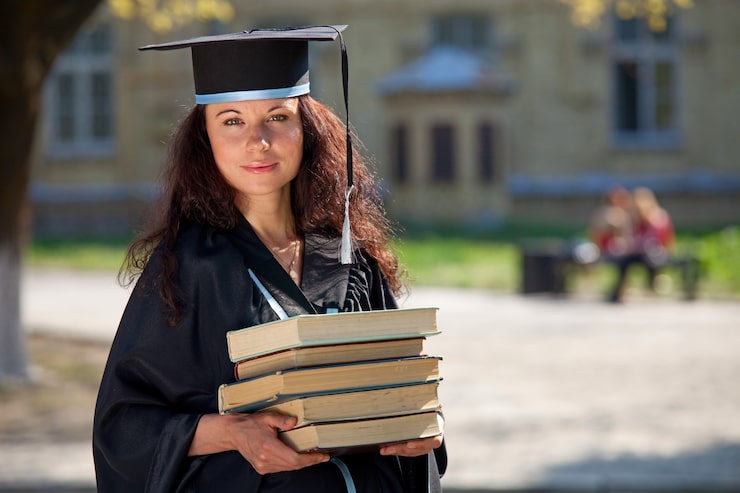 Foto de afgestudeerde met boeken op de binnenplaats van een universiteit
