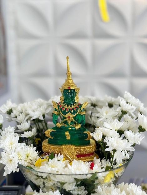 Photo พระแก้วมรกตมีขนาดไม่ใหญ่ วางอยู่บนถาดล้อมรอบด้วยดอกไม้