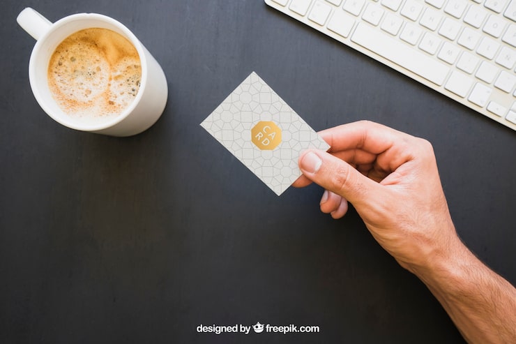 PSD grátis mock up da mão segurando cartão de visita com café e teclado