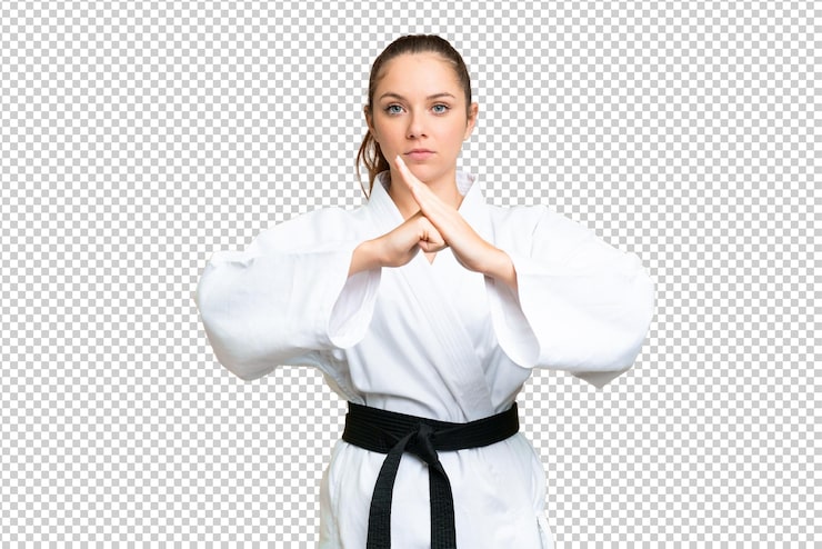 PSD giovane donna bionda su sfondo chroma key isolato facendo karate e salutando
